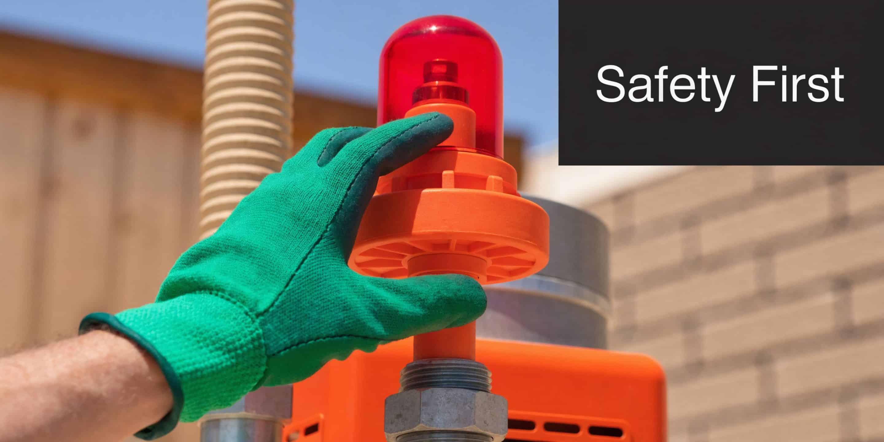 A gloved hand inspects an orange safety beacon light installed on a home heating system unit.